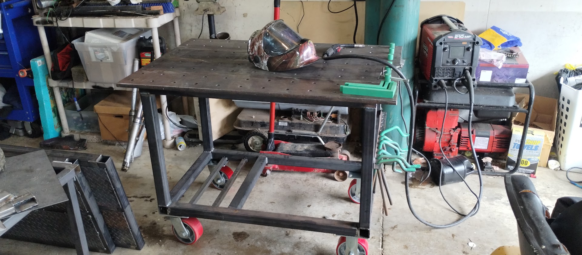 A shop-built steel welding table on castors with a welding helmet resting on it